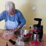 Starejša ženska med pripravo rdečega napitka.