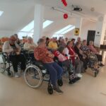 Več starejših ljudi sedi na invalidskih vozičkih.