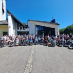 Večja skupina ljudi z vozički in brez pred stavbo.