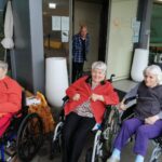 Tri starejše ženske sedijo na invalidskih vozičkih.