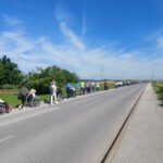 Dolga kolona ljudi, ki spremljajo starejše ljudi na vozičkih na prostem.