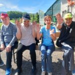 3 moški in ženska sedijo na klopci na prostem.