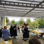 Dva para v narodnih nošah plešeta pred več ljudmi na prostem.
