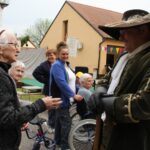 Več ljudi stoji zraven moškega, ki je oblečen v meščanska oblačila.