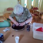 Starejša gospa pripravlja višnje za vlaganje.