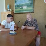 Dva moška sedita za mizo in gledata v mobilni telefon.