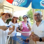 Tri ženske in moški stojijo pod marelo in v rokah držijo kornet s sladoledom.