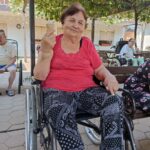 Ženska sedi na invalidskem vozičku in v rokah drži kornet s sladoledom.