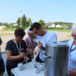Več ljudi pripravlja skodelice s smetano in sladoledom.