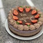 Čokoladna torta s čokoladno kremo in svežimi jagodami na vrhu. Na sredini torte je napisano "Vse najboljše".