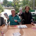 Tri nasmejane starejše ženske ponosno kažejo nagrade, ki so jih prejele pri tomboli.