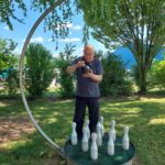 Moški na prostem pripravlja kroglo za podiranje kegljev na krožni konstrukciji v zelenem parku.