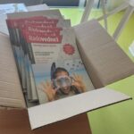 Škatla, napolnjena s promocijskimi izdajami revije Radovednež z naslovnico, na kateri je nasmejana oseba z masko za potapljanje.