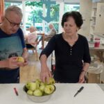 Starejši moški in ženska pripravljata jabolka za kuhanje v skupnem prostoru doma za starejše.