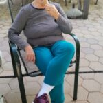 Starejša gospa uživa v sladoledu na terasi doma starejših.