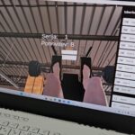 Zaslon prenosnika prikazuje virtualno okolje z utežmi, uporabnik vidi lastne noge v simulaciji vadbe.