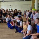 Skupinska slika stanovalcev, prostovoljcev in glasbenikov, vsi se smejijo.