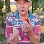 Stanovalec med malico na prostem uživa v pečeni klobasi ‘pasja radost’ s kruhom.