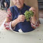 Stanovalka doma drži grozd svežega zelenega grozdja.