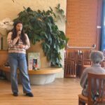 Oseba z mikrofonom bere ali pripoveduje zgodbo pred poslušalci v dvorani doma.