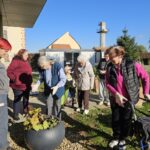 Skupina oseb se druži na sončen dan ob zasaditvi cvetličnega korita na vrtu doma.