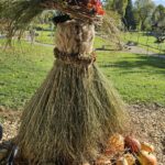 Jesenska dekoracija iz slame, buč in cvetja stoji na vrtu doma v sončnem vremenu.