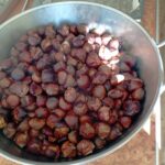 Velika posoda s pečenimi kostanji pripravljenimi za postrežbo.