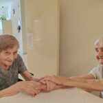 Dve stanovalke se nasmejano držita za roke ob zaključku nege rok.