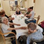 Stanovalke in zaposlena med nego rok ob prijetnem druženju v skupnem prostoru.