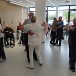 Stanovalci in zaposleni skupaj plešejo ob glasbi na Mini Oktoberfestu v domu.