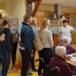 Skupina obiskovalcev si ogleduje dejavnosti v bivalnem prostoru doma.