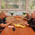 Stanovalke skupaj obrezujejo in luščijo krompir za pripravo kosila.