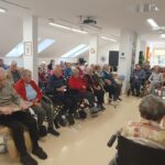 Skupina stanovalcev posluša branje pravljice v skupnem prostoru doma.