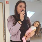 Oseba z mikrofonom drži lutko med pripovedovanjem zgodbe.