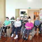 Skupina stanovalcev sodeluje na predstavitvi delovne terapije v jedilnici doma.