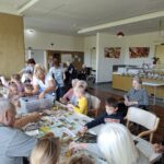 Skupina otrok in starejših oseb ustvarja z jesenskim listjem v večnamenskem prostoru doma.