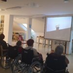 Stanovalci in stanovalki si skupaj ogledujejo film, ki se predvaja na velikem platnu.