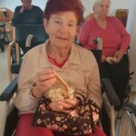 Stanovalka z nasmehom drži skledo pokovke in piškot med filmskim večerom.