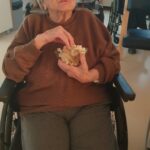 Stanovalka uživa ob ogledu filma s skledo pokovke v naročju.