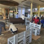 Stanovalci in zaposleni skupaj barvajo lesene klopi na dvorišču doma.