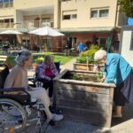 Stanovalke na dvorišču doma sodelujejo pri vrtnarjenju.