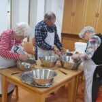 Stanovalci skupaj pripravljajo zelenjavo in ribajo redkev v kuhinji doma.