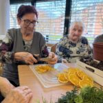 Stanovalka s škarjami reže posušene pomaranče za izdelavo adventnih venčkov.