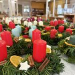 Adventni venčki z rdečimi svečami in naravnimi okraski, razstavljeni na mizi.