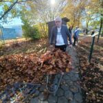 Stanovalec potiska samokolnico, polno zbranega jesenskega listja.