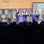 Oder s skupino Domače melodije, ki nastopa pred številnim občinstvom v športni dvorani.