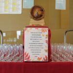 Sodček vina z napisano pesmico in pripravljenimi kozarci za martinovanje.