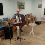 Glasbenik igra na harmoniko v dvorani doma.