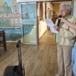 Stanovalka bere besedilo v mikrofon med prireditvijo v jedilnici.