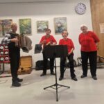 Zunanja glasbena skupina nastopa s harmoniko, ropotuljami in petjem pred stanovalci doma.